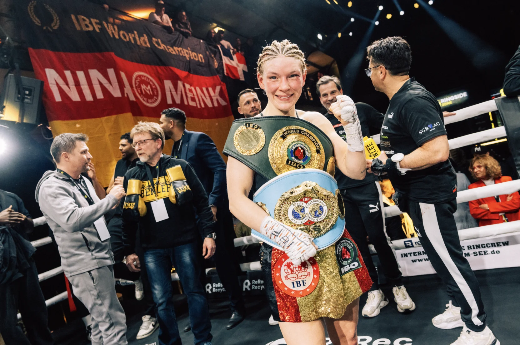 Nina Meinke lächelt und trägt ein kariertes Hemd mit einem neutralen Hintergrund.