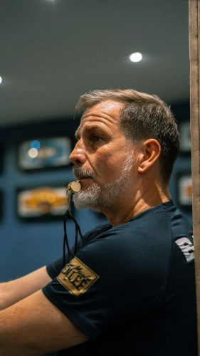 Ein Mann mit grauem Bart hält im Meinke Gym einen Mundschutz zwischen den Lippen und blickt konzentriert zur Seite.